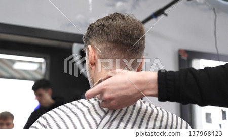 Skilled barber trimming client's neck hairline, wielding straight razor with expertise in traditional, vintage style barbershop setting 137968423