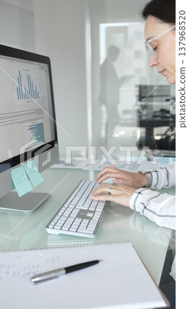 Woman analyst working on computer, analyzing business data with charts and graphs, marketing report on screen. Businesspeople concept 137968520