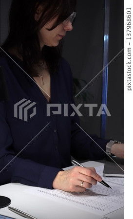 Woman's hands typing on laptop at office desk, working late night with calculator and financial documents. Audit and taxes in business 137968601
