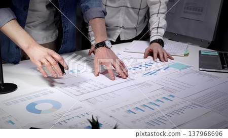 Business professionals analyzing financial data and market trends, reviewing growth charts, and developing strategic plans for company success while collaborating on paperwork Business professionals analyzing financial data and market trends, reviewing growth charts, and developing strategic plans for company success while collaborating on paperwork 137968696