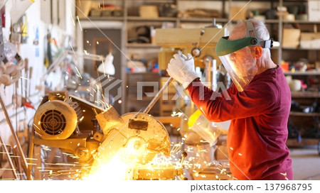 Senior metalworker cutting metal in workshop creating sparks Senior metalworker cutting metal in workshop creating sparks 137968795