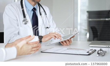 Doctor man interacting with patient during consultation, using digital tablet for modern medical healthcare technology. Medicine, healthcare and science concept Doctor man interacting with patient during consultation, using digital tablet for modern medical healthcare technology. Medicine, healthcare and science concept 137968800
