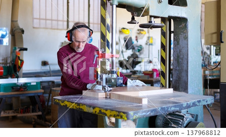 Senior carpenter cutting wood using a band saw Senior carpenter cutting wood using a band saw 137968812