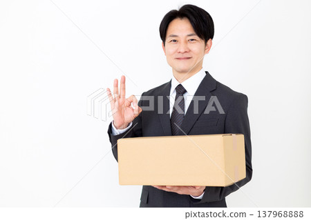A middle-aged businessman makes a circular pose while holding cardboard boxes. A middle-aged businessman makes a circular pose while holding cardboard boxes. 137968888