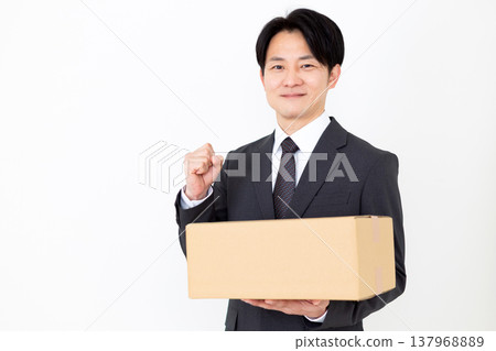 A middle-aged businessman makes a triumphant gesture while holding a cardboard box. A middle-aged businessman makes a triumphant gesture while holding a cardboard box. 137968889