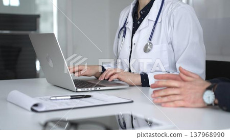 Doctor woman consulting male patient using laptop, discussing health information during medical examination at clinic office. Medicine, healthcare and science concept Doctor woman consulting male patient using laptop, discussing health information during medical examination at clinic office. Medicine, healthcare and science concept 137968990