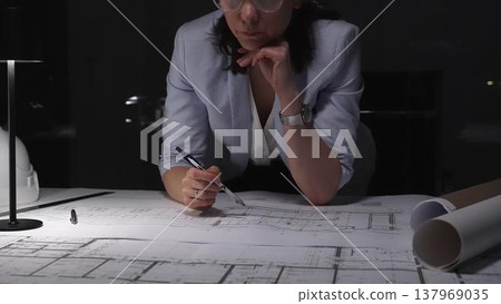 Female architect drawing blueprints for new building design, working late in office, creating architectural plans. Female architect drawing blueprints for new building design, working late in office, creating architectural plans. 137969035