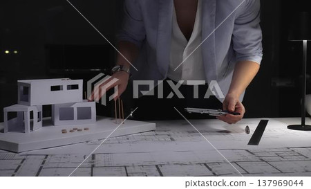 Female architect working on blueprints and house model, planning modern residential construction design project. Business and architect people concept 137969044