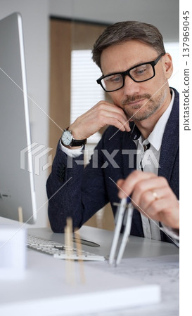 Professional architect drafting blueprints at a desk, holding a compass, focusing on structural plans and urban design. Business and architecture concept 137969045