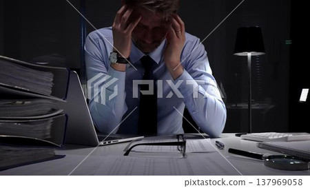 Stressed businessman suffering from headache and occupational burnout working late in a dark office. Audit and taxes in business 137969058