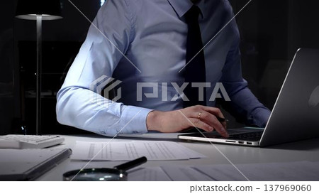 Businessman working overtime in office signing document at night, preparing contracts and finances. Audit and taxes in business Businessman working overtime in office signing document at night, preparing contracts and finances. Audit and taxes in business 137969060