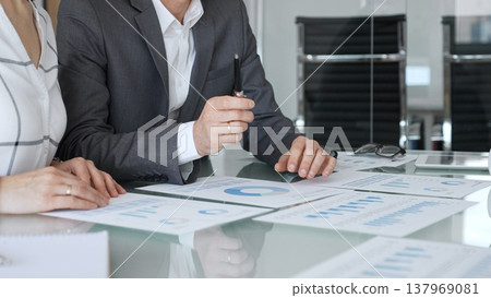 Business professionals analyzing financial data, discussing market trends and economic reports in a corporate meeting setting. Business-people concept 137969081