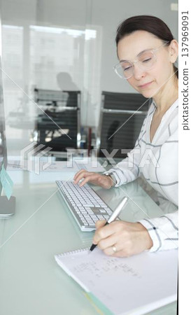 Businesswoman at glass office desk analyzing charts and graphs on computer screen, reviewing financial reports and performance data for planning. Business people concept Businesswoman at glass office desk analyzing charts and graphs on computer screen, reviewing financial reports and performance data for planning. Business people concept 137969091