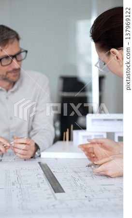 Architects are teamwork planning a building design project, reviewing detailed blueprints with a compass and a ruler, working on technical drawings and a digital tablet at the office, close up Architects are teamwork planning a building design project, reviewing detailed blueprints with a compass and a ruler, working on technical drawings and a digital tablet at the office, close up 137969122