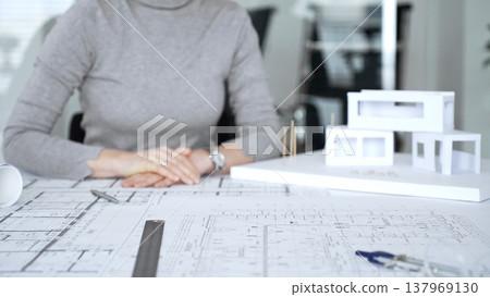 Handshaking between two architects finalizing a construction project deal, business partners agreeing on engineering blueprints and architectural models in an office, close up Handshaking between two architects finalizing a construction project deal, business partners agreeing on engineering blueprints and architectural models in an office, close up 137969130