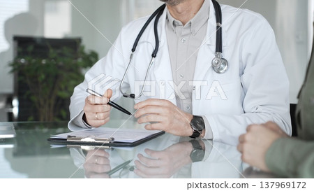 Doctor and patient discussing medical diagnosis, providing healthcare advice during consultation in clinic office. Medicine, health care and science concept Doctor and patient discussing medical diagnosis, providing healthcare advice during consultation in clinic office. Medicine, health care and science concept 137969172