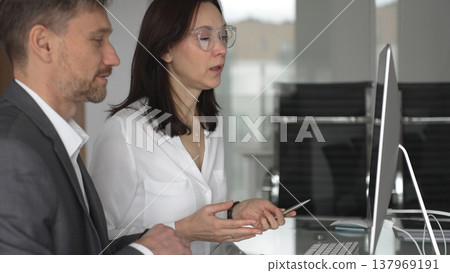 Business colleagues collaborating on a project, analyzing data and discussing financial strategy during an office meeting, focusing on shared screens and teamwork. Businesspeople concept Business colleagues collaborating on a project, analyzing data and discussing financial strategy during an office meeting, focusing on shared screens and teamwork. Businesspeople concept 137969191