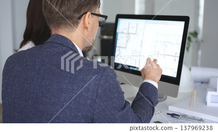 Architecture and engineering team collaborating on project blueprints using computer aided design software in an office. Business and architecture concept 137969238