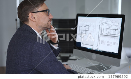 Architect working on building blueprint plans, creating design and engineering structure on desktop computer in office. Business and architecture concept Architect working on building blueprint plans, creating design and engineering structure on desktop computer in office. Business and architecture concept 137969292