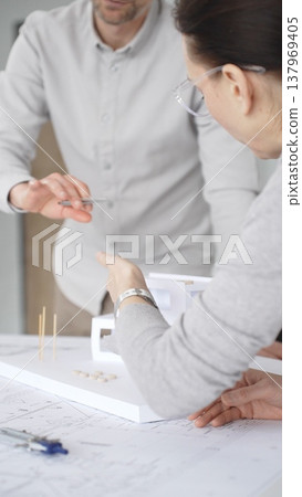 Architects are discussing building plans, using a compass over blueprints while collaborating on a new construction project in an office, emphasizing design, planning, and teamwork, close up 137969405