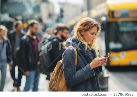Person checking smartphone while waiting for public transport in city environment 137969582