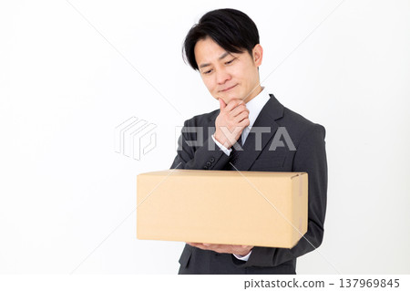 A middle-aged businessman struggling with cardboard boxes. 137969845
