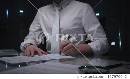 Business man signing a contract late in the office, closing a deal, or completing legal paperwork at deep night. Audit and overworking concepts Business man signing a contract late in the office, closing a deal, or completing legal paperwork at deep night. Audit and overworking concepts 137970042