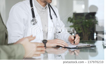 Doctor man writing prescription during patient consultation in clinic, providing medical advice and healthcare service. Medicine, health care and science concept 137970210