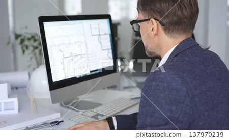 Architecture and engineering team collaborating on project blueprints using computer aided design software in an office. Business and architecture concept Architecture and engineering team collaborating on project blueprints using computer aided design software in an office. Business and architecture concept 137970239