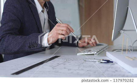 Architect hand drawing on building blueprints, creating an architectural model, and using a computer for project design. Business and architecture concept Architect hand drawing on building blueprints, creating an architectural model, and using a computer for project design. Business and architecture concept 137970282