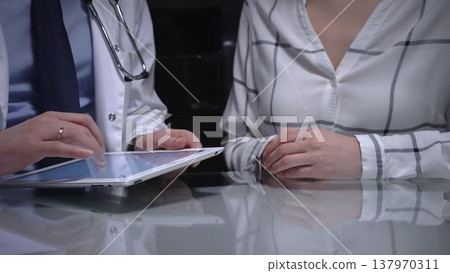 Doctor discussing medical information with a patient during a consultation, using a modern tablet for digital healthcare data and electronic health records 137970311