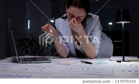 Stressed business woman suffering from headache in dark office, hands on head experiencing burnout and fatigue during late night work, facing deadline pressure and financial difficulties Stressed business woman suffering from headache in dark office, hands on head experiencing burnout and fatigue during late night work, facing deadline pressure and financial difficulties 137970358