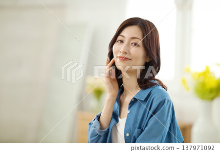 A middle-aged woman smiles at the camera in her living room. 137971092