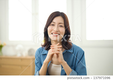 一位中年婦女在客廳對著鏡頭微笑。 一位中年婦女在客廳對著鏡頭微笑。 137971096