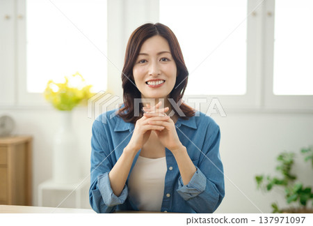 一位中年婦女在客廳對著鏡頭微笑。 一位中年婦女在客廳對著鏡頭微笑。 137971097