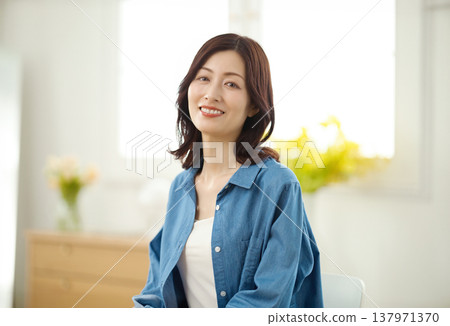 一位中年婦女在客廳對著鏡頭微笑。 一位中年婦女在客廳對著鏡頭微笑。 137971370