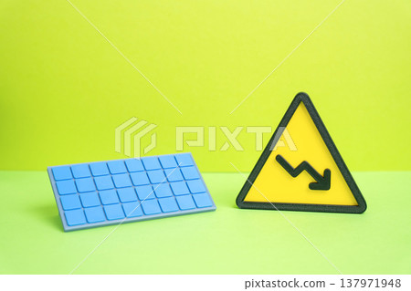 Solar panel and a downward arrow. Falling prices for solar technology and renewable energy equipment. Lower production costs but also reduced generation due to weather conditions or technical failures 137971948