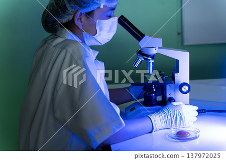 The scientist biologist is working very seriously use microscope 137972025