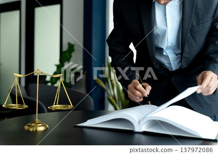 The lawyer is standing and looking at the papers prepared on the table 137972086