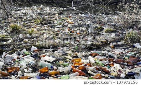 Dirty river is polluted with many plastic bottles. A lot of trash is dumped in open and freely available places at nature. Global environmental pollution problem. Concept of ecological disaster 137972156