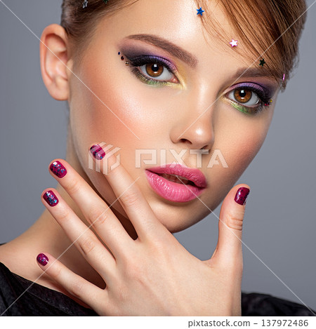 Portrait of a beautiful woman with bright makeup. Closeup female face with purple eye make-up. Pretty, sexy girl with violet nails near face. Stylish fashion model with a short slick hair 137972486