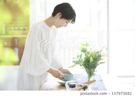 一位年輕女子正忙著日常生活，擺放餐具準備用餐。 137973082