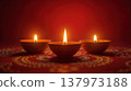 Three simple clay diya lamps lit for Diwali pooja on a clean red background 137973188