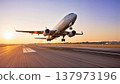 Low angle view of a passenger airplane taking off from a runway during a beautiful golden sunset. 137973196