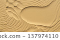 Rippled sand textures form abstract patterns across a warm golden surface in this close up of a vast and arid desert landscape scene. 137974110