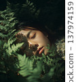 Peaceful Asian Woman Resting Among Lush Green Fern Leaves in Forest 137974159