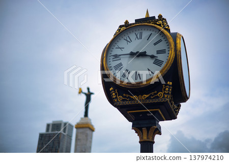 Vintage Street Clock with Roman Numerals and Golden Ornaments, Classic Architectural Detail of Outdoor Public Timepiece against Cloudy Sky, Historical City Navigation and Timekeeping Element Vintage Street Clock with Roman Numerals and Golden Ornaments, Classic Architectural Detail of Outdoor Public Timepiece against Cloudy Sky, Historical City Navigation and Timekeeping Element 137974210