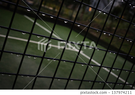 Close-up of Metal Fence with Raindrops on Green Sports Field Background, Abstract Grid Pattern with Water Droplets, Outdoor Tennis Court or Football Pitch during Rainy Weather Details Close-up of Metal Fence with Raindrops on Green Sports Field Background, Abstract Grid Pattern with Water Droplets, Outdoor Tennis Court or Football Pitch during Rainy Weather Details 137974211