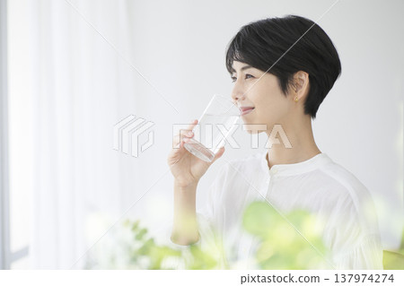 A young woman going about her daily life: drinking a glass of water - a healthy lifestyle A young woman going about her daily life: drinking a glass of water - a healthy lifestyle 137974274