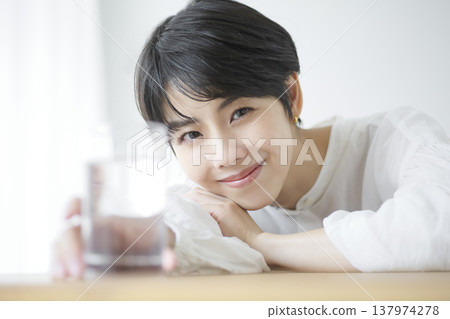 A young woman going about her daily life, relaxing indoors and drinking water. A young woman going about her daily life, relaxing indoors and drinking water. 137974278